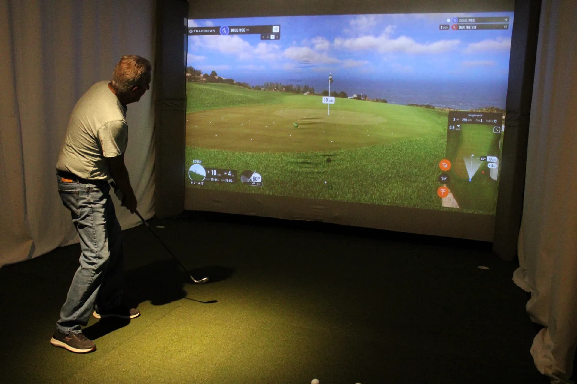 Golfer chipping on a seaside course in a TrackMan simulator at Gonzo's