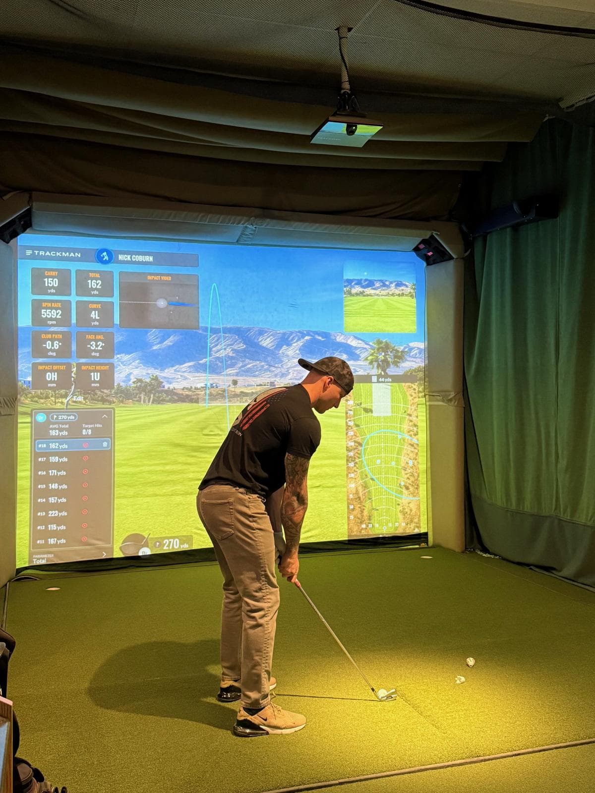 Golfer mid-swing at TrackMan simulator