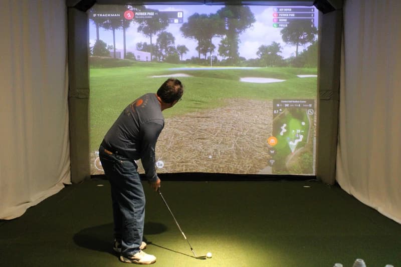 Player in polo shirt using TrackMan golf simulator