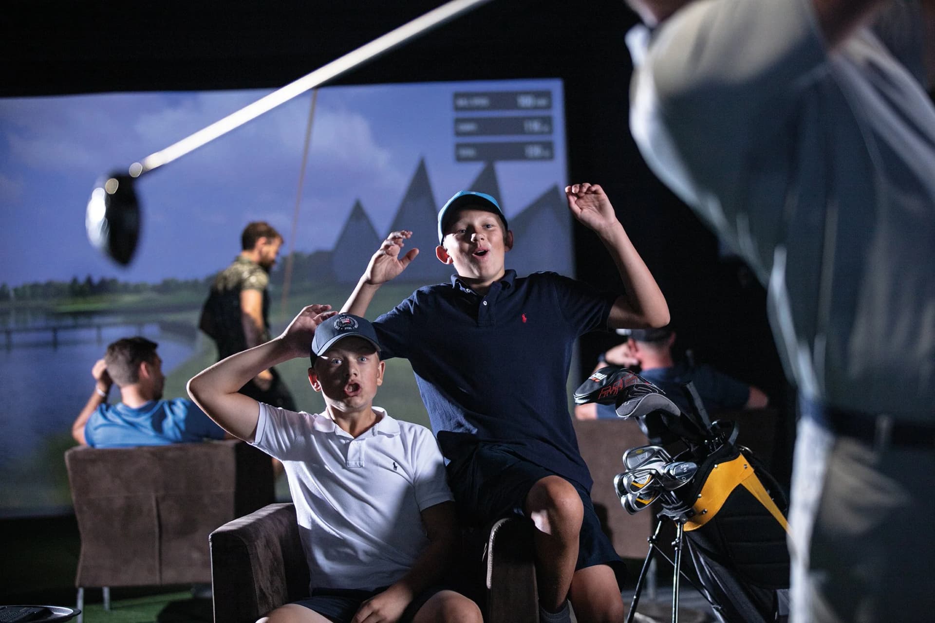 Children cheering and celebrating at a TrackMan simulator
